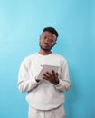 A young African-American man with glasses writes down information in a notebook on a blue background Royalty Free Stock Photo