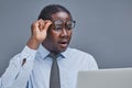 young african american man on a gray background looking at a laptop in surprise Royalty Free Stock Photo