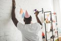 young african american man with hammer nailing up string with party garland on brick