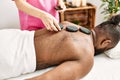 Young african american man having back massage with hot stones at beauty center Royalty Free Stock Photo