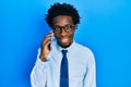 Young african american man having conversation talking on the smartphone looking positive and happy standing and smiling with a Royalty Free Stock Photo