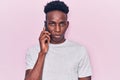 Young african american man having conversation talking on the smartphone thinking attitude and sober expression looking self Royalty Free Stock Photo