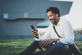 Young African American man in headphone sitting at sunny city park and enjoying to listen to music on his smart phone Royalty Free Stock Photo