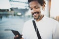Young African American man in headphone walking at sunny city and enjoying to listen to music on his smart phone.Blurred Royalty Free Stock Photo