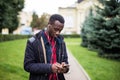 Young African American man in headphone walking at sunny city and enjoying to listen to music on his smart phone. Royalty Free Stock Photo