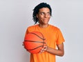 Young african american man holding basketball ball smiling looking to the side and staring away thinking Royalty Free Stock Photo
