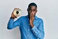 Young african american man holding compact disc covering mouth with hand, shocked and afraid for mistake Royalty Free Stock Photo