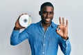 Young african american man holding compact disc doing ok sign with fingers, smiling friendly gesturing excellent symbol Royalty Free Stock Photo