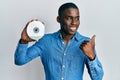 Young african american man holding compact disc pointing thumb up to the side smiling happy with open mouth Royalty Free Stock Photo