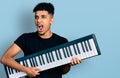 Young african american man holding piano keyboard angry and mad screaming frustrated and furious, shouting with anger Royalty Free Stock Photo