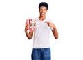 Young african american man holding popcorn smiling happy pointing with hand and finger Royalty Free Stock Photo