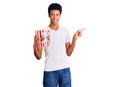 Young african american man holding popcorn smiling happy pointing with hand and finger to the side Royalty Free Stock Photo