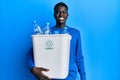 Young african american man holding recycling wastebasket with plastic bottles looking positive and happy standing and smiling with Royalty Free Stock Photo