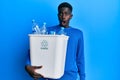 Young african american man holding recycling wastebasket with plastic bottles scared and amazed with open mouth for surprise, Royalty Free Stock Photo