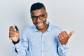 Young african american man holding removable memory usb pointing thumb up to the side smiling happy with open mouth Royalty Free Stock Photo