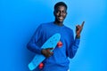 Young african american man holding skate smiling happy pointing with hand and finger to the side Royalty Free Stock Photo