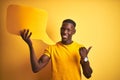 Young african american man holding speech bubble standing over isolated yellow background pointing and showing with thumb up to Royalty Free Stock Photo