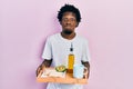 Young african american man holding tray with breakfast food puffing cheeks with funny face Royalty Free Stock Photo