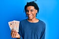 Young african american man holding 10 united kingdom pounds banknotes looking positive and happy standing and smiling with a