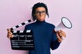 Young african american man holding video film clapboard and megaphone depressed and worry for distress, crying angry and afraid