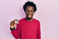 Young african american man holding virtual currency ethereum coin looking positive and happy standing and smiling with a confident
