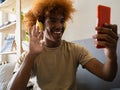 Young African American man at home on the couch making a video call with smartphone Royalty Free Stock Photo