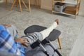 Young African American man with an injured leg and foot sitting on the couch at home Royalty Free Stock Photo