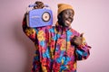 Young african american man listening to music holding portable vintage retro radio pointing and showing with thumb up to the side Royalty Free Stock Photo