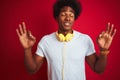 Young african american man listening to music using headphones over isolated red background relax and smiling with eyes closed Royalty Free Stock Photo