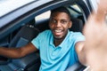 Young african american man making selfie by the camera sitting on car at street Royalty Free Stock Photo