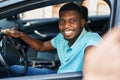 Young african american man making selfie by the camera sitting on car at street Royalty Free Stock Photo