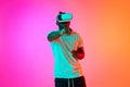 Young african american man play video games in VR-glasses showing his fist to camera over pink-orange background in neon Royalty Free Stock Photo