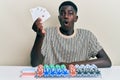 Young african american man playing poker holding cards scared and amazed with open mouth for surprise, disbelief face Royalty Free Stock Photo