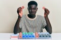 Young african american man playing poker holding casino chips puffing cheeks with funny face Royalty Free Stock Photo