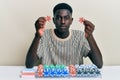 Young african american man playing poker holding casino chips relaxed with serious expression on face Royalty Free Stock Photo
