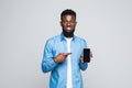 Young African American man pointing his smartphone screen isolated on gray background Royalty Free Stock Photo