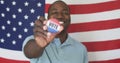 A young African American man proudly displays a voters badge