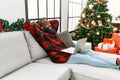 Young african american man relaxed with hands on head sitting by christmas tree at home Royalty Free Stock Photo