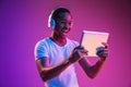 Young african-american man`s listening to music in neon light