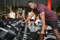 Young African American man sitting and lifting a dumbbell close to the rack at gym. Male weight training person doing a Royalty Free Stock Photo