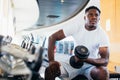 Young African American man sitting and lifting a dumbbell with the rack at gym Royalty Free Stock Photo