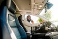 Young African American man in smart casual business wear, using phone sitting in the car, side view Royalty Free Stock Photo