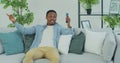 Young African American man with smartphone making video call while sitting on couch in living room. Portrait of happy Royalty Free Stock Photo