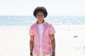 A young African American man smiles brightly on a sunny beach, unaltered