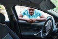Young african american man smiling confident looking car leaning on door at street Royalty Free Stock Photo