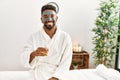 Young african american man smiling happy with facial mask drinking champagne at beauty center Royalty Free Stock Photo