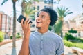 Young african american man smiling happy sending audio message using smartphone at the city Royalty Free Stock Photo