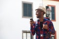 Young african american man smiling with mobile phone while walking on street with backpack Royalty Free Stock Photo