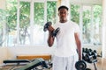 Young African American man standing and lifting a dumbbell with the rack at gym Royalty Free Stock Photo