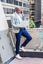 Young African American man talking on cell phone, working on laptop computer outside in New York City Royalty Free Stock Photo